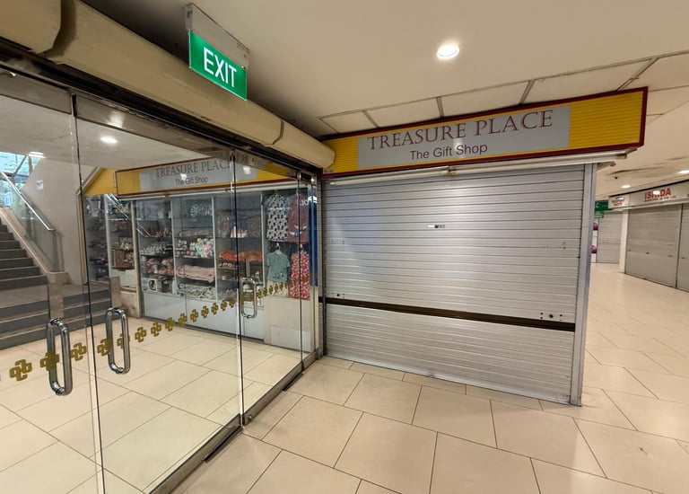 Treasure Place gift shop storefront with metal rolling shutters and glass doors in a shopping mall.