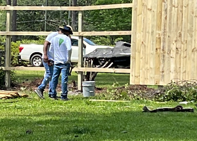man working carpentry on wooden fence wearing garnetpainti remodeling company shirts