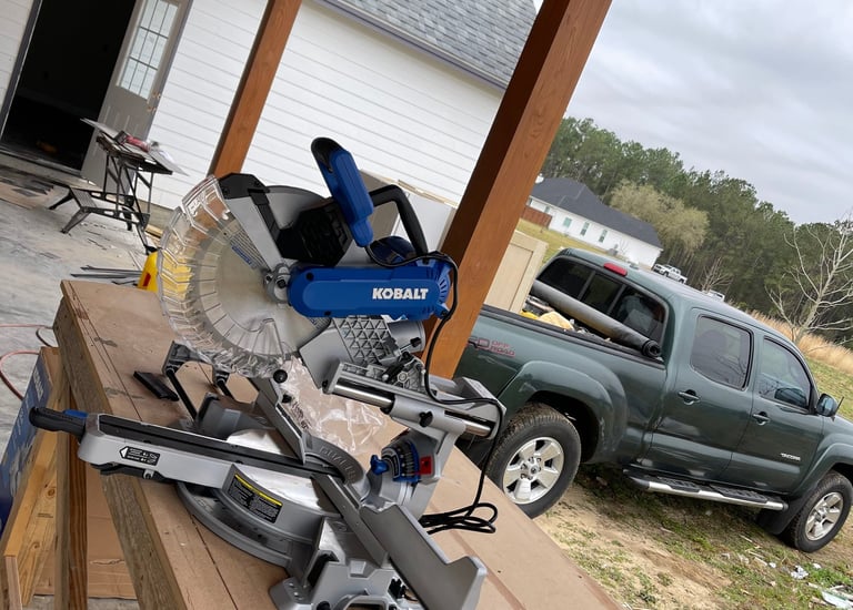 A professional woodworking saw on a table and a van with cabinets and fine interior lumber.