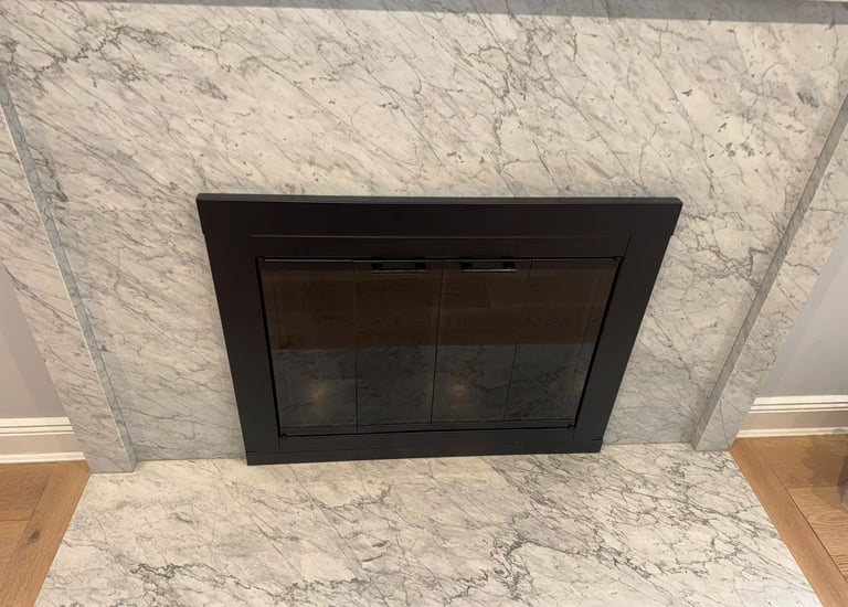 A completed fireplace project featuring a new black fireplace insert and a custom-installed marble s