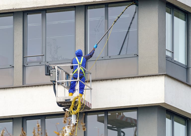 Un laveur de vitres, utilise une perche à eau pure pour nettoyer les menuiseries extérieur
