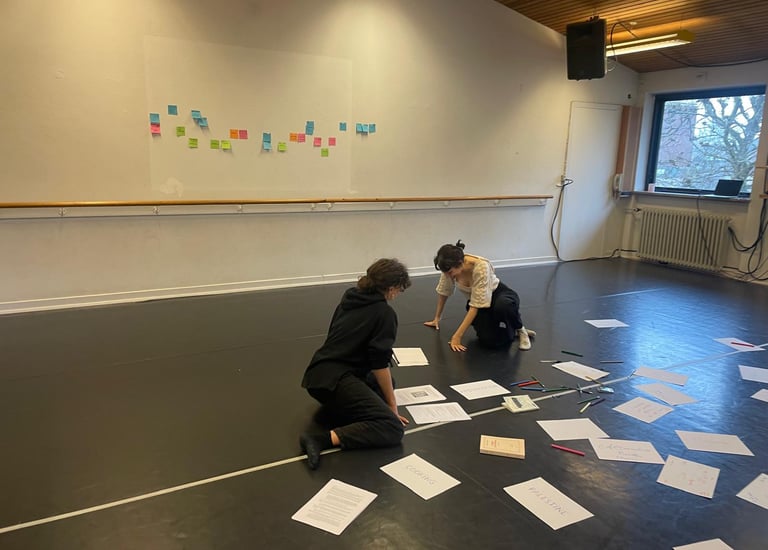 Due persone inginocchiate tra fogli e post-it colorati in uno studio luminoso