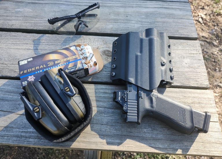Eye and ear protection, self-defense ammunition, holstered self-defense firearm with red dot.