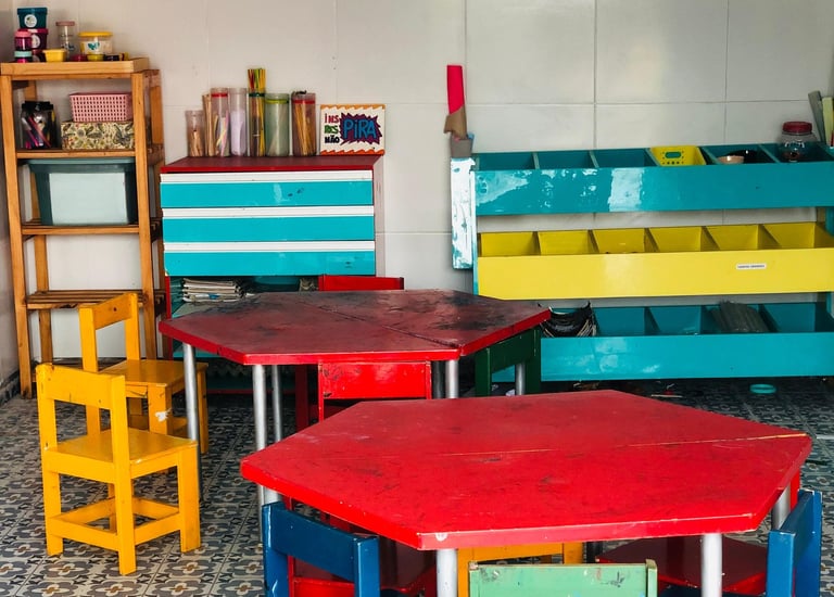 Mesinhas e bancos coloridos em uma sala de artes infantil