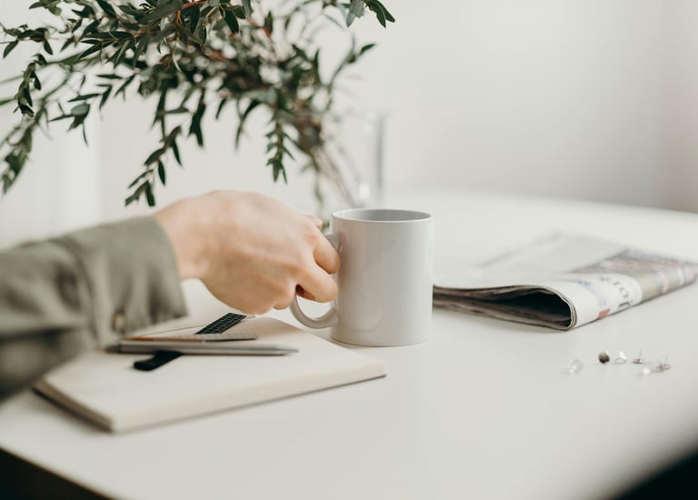 Hand bij koffie en notitieblok, mini-moment van zelfreflectie.