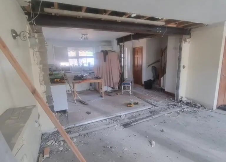 Open plan home renovation showing a structural steel beam installation and wall removal in a house.