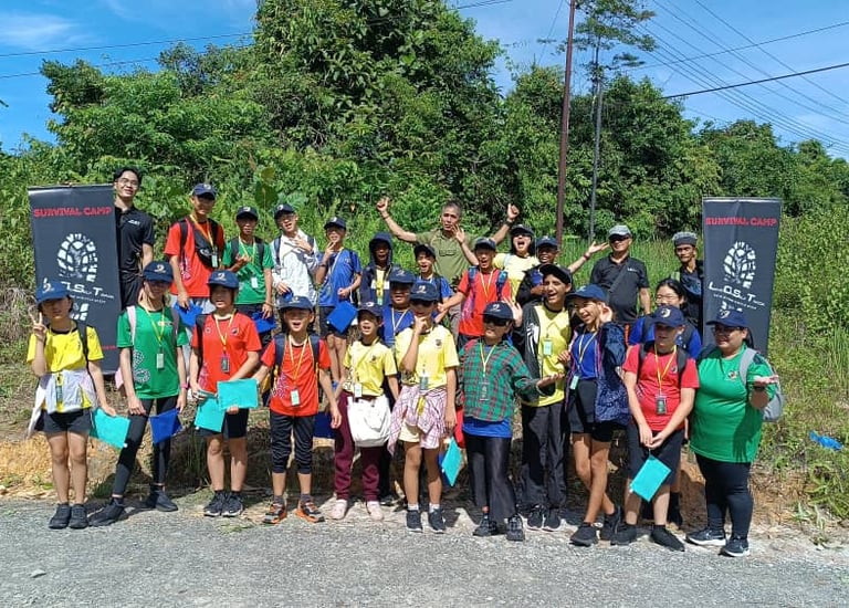 a group of students standing in front of a lost borneo tours bunting