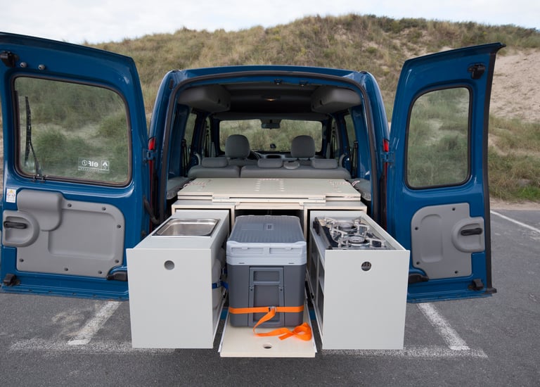 1st prototype WOODSYBOX with pull-out kitchen drawers, portable fridge, and sink unit in a blue van.
