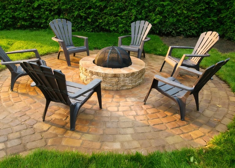 Foyer extérieur circulaire en pierre avec chaises Adirondack sur terrasse en pavés par M2 Paysage