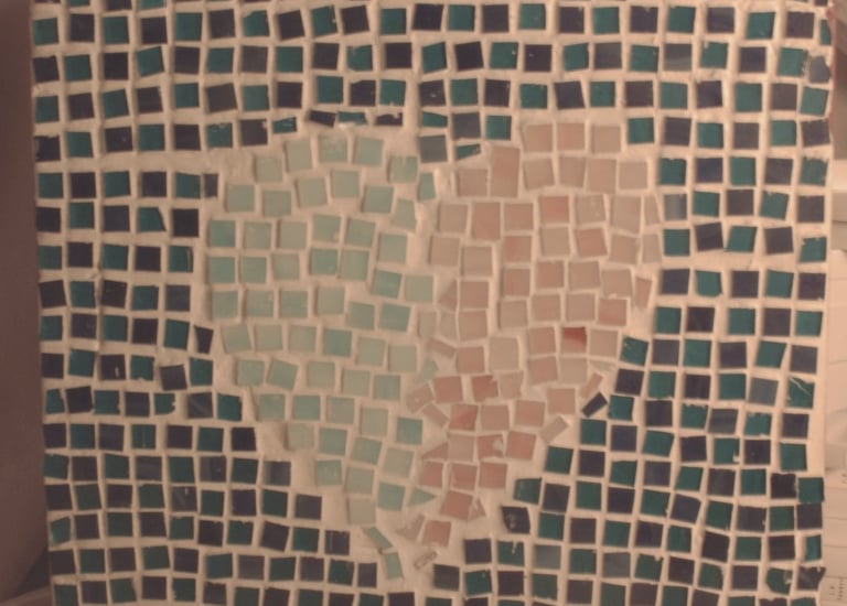 Handmade mosaic tile art featuring a light blue and pink heart on a dark blue square background.