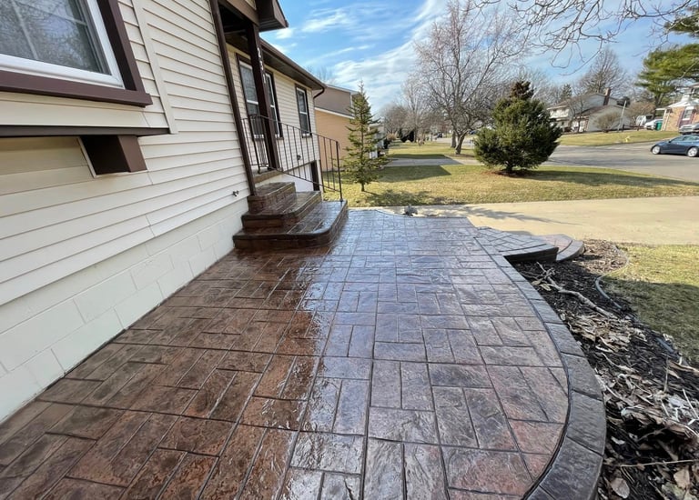 Custom stamped concrete patio with ashlar slate pattern and curved border in a residential backyard.