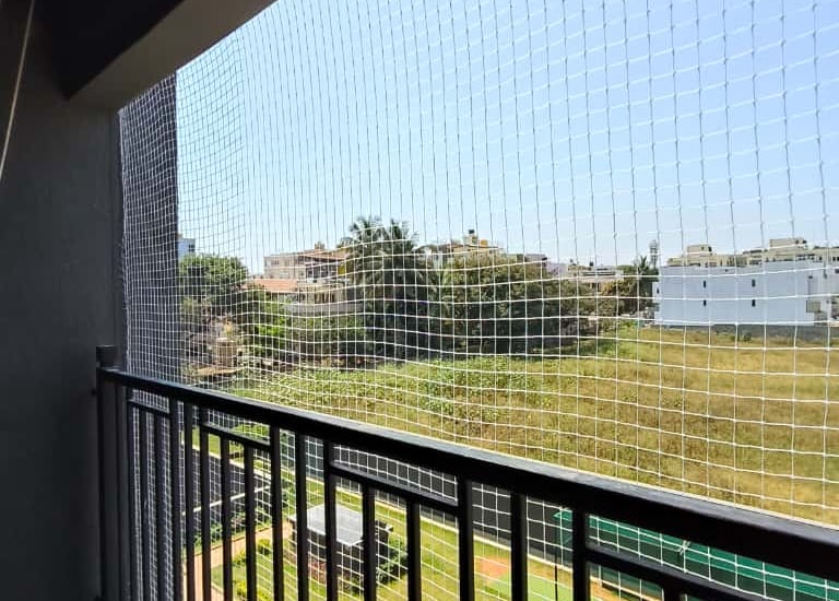 Close-up shot of sturdy pigeon netting stretched over a balcony railing, bright sunlight highlightin
