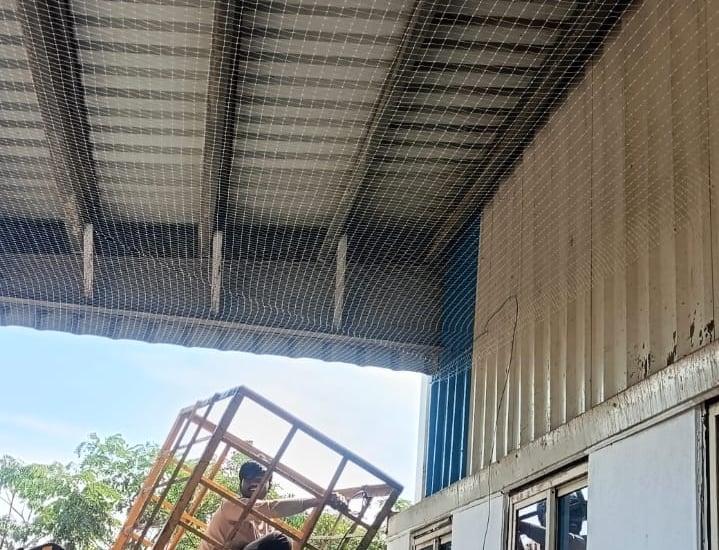 Image capturing the protective safety nets casting shadows over stacked warehouse goods.