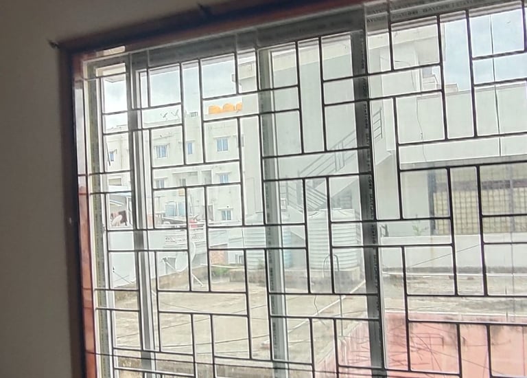 A technician from Arjilli Safety Nets installing a mosquito net on a window frame.