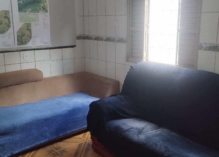 Small living room with tiled walls featuring a blue sofa and a tan daybed couch by a window.