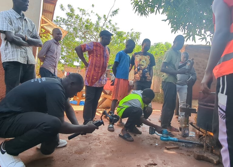 A film crew records a community vocational training session outdoors using a gimbal and professional camera equipment.