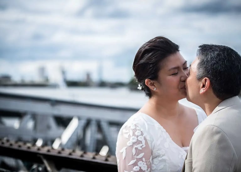 Two brides share a kiss during an outdoor wedding photo shoot in Greenwich