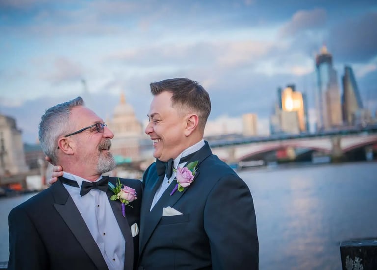 two grooms smiling at each other on london Southbank