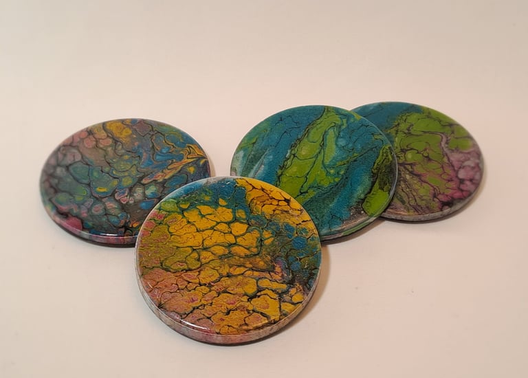 Set of four round handmade resin coasters featuring colorful fluid acrylic pour art designs.