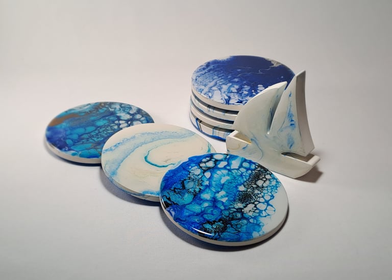 Handmade blue and white resin ocean coasters with cells and a small sailboat figurine.