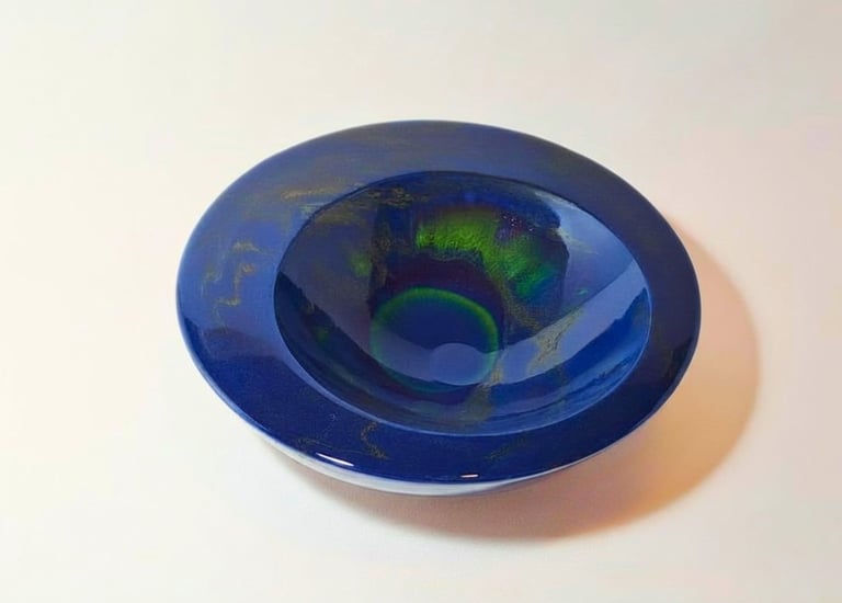 Handmade deep blue gypsum decorative bowl with iridescent northern lights green swirling effects.