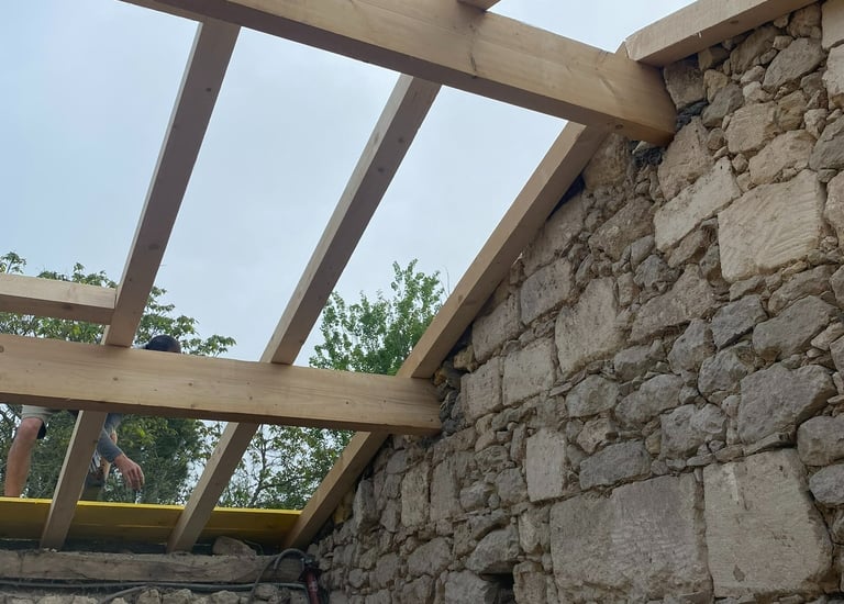 De nouvelles poutres en bois ont été installées sur un mur en pierre rustique pour un projet de réno