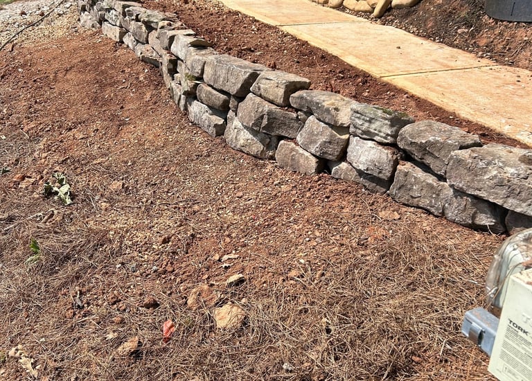 Natural boulder wall holding back soil.