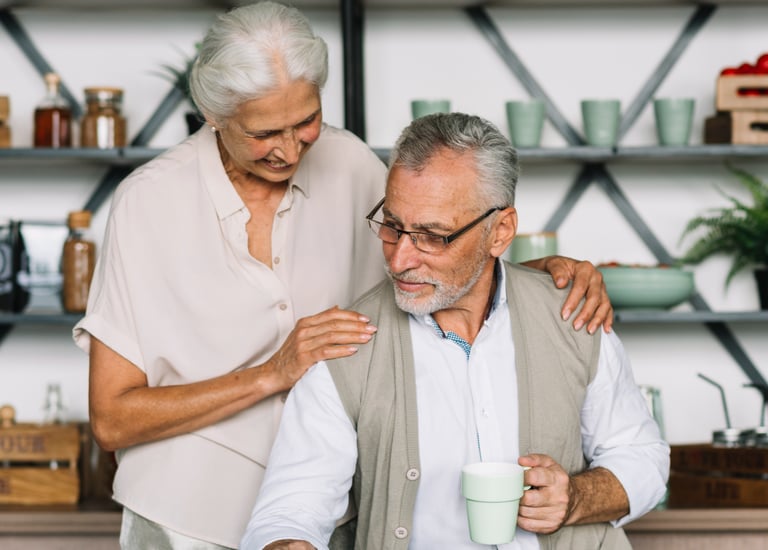 A happy senior couple reading a newspaper and drinking coffee in a modern kitchen.