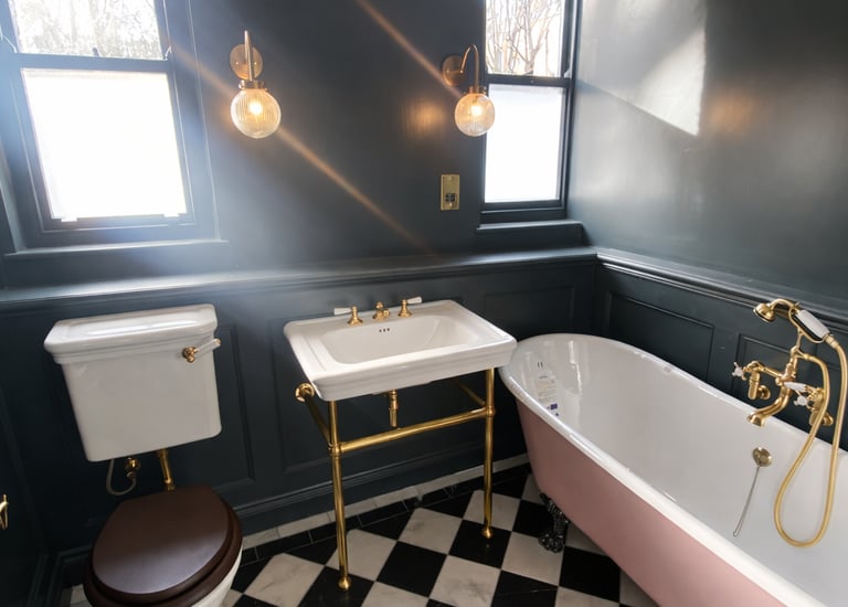 Luxury bathroom with a pink clawfoot tub, gold fixtures, and black and white checkered floor tiles.