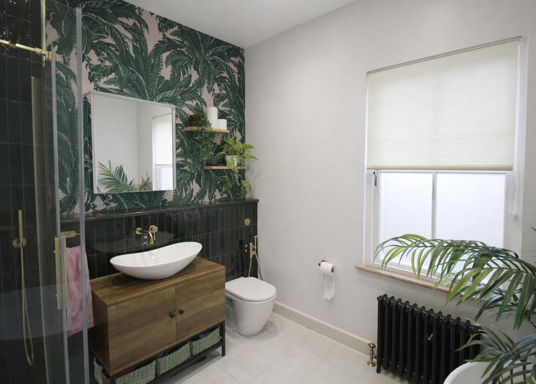 Modern bathroom featuring tropical palm leaf wallpaper, a wooden vanity, and gold fixtures.