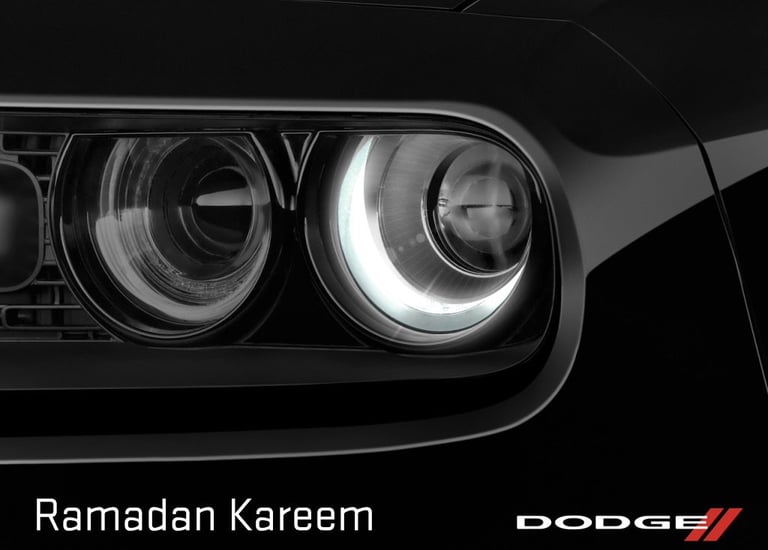 Close-up of a black Dodge Challenger headlight with Ramadan Kareem text and brand logo.