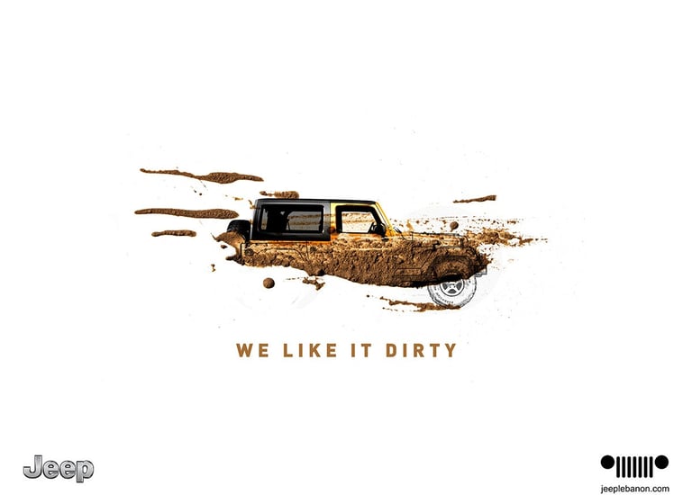 Jeep 'We Like It Dirty' creative ad showing a mud-splattered Jeep, emphasizing rugged performance.