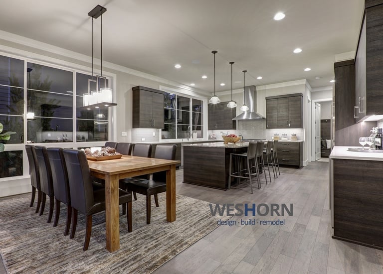 Modern open concept kitchen and dining room featuring dark wood cabinets and a rustic oak table.