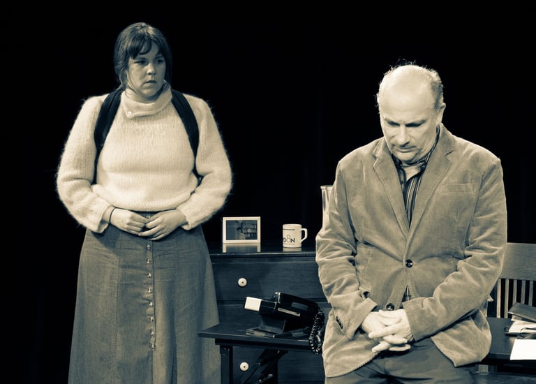 Man leaning on desk with woman standing behind.