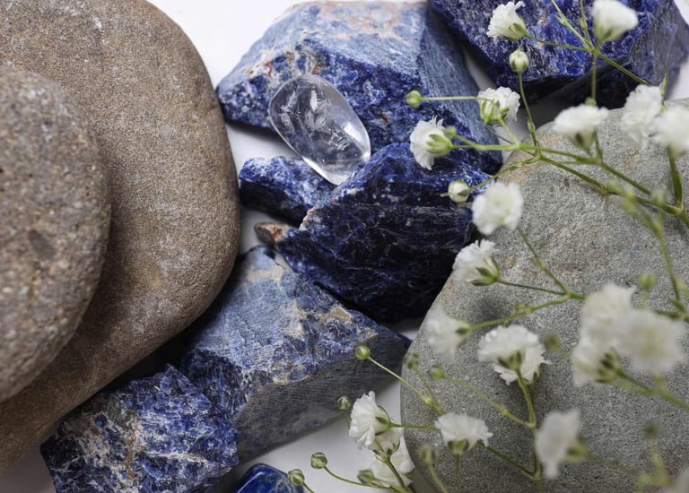 Piedras naturales de sodalita azul acompañadas de piedras de río y flores de gypsophila blanca.