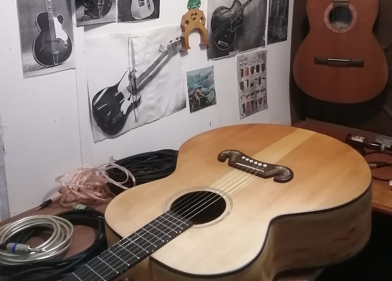 Guitarra elaborada artesanalmente en mesa de trabajo con herramientas y repuestos. lutheria