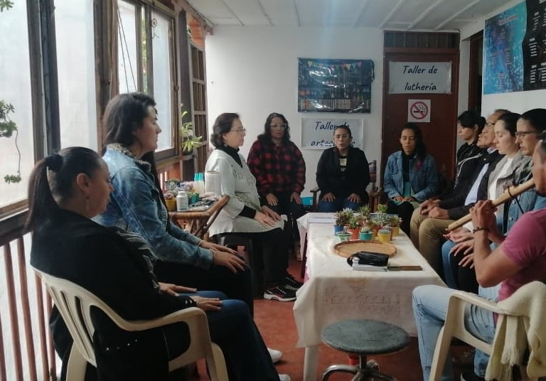Personas en talle de cuidado de plantas durante el momento de armonización musical. Hay plantas