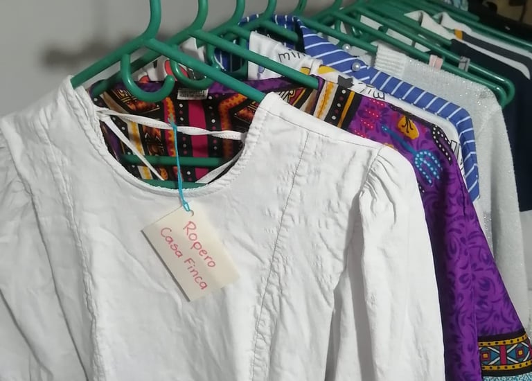 Blusa blanca y ropa vintage con estampados coloridos en perchas verdes dentro de una tienda boutique