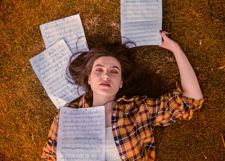 Dans ce projet photo Denis Studio, une jeune artiste musicienne repose sur l’herbe, regard caméra