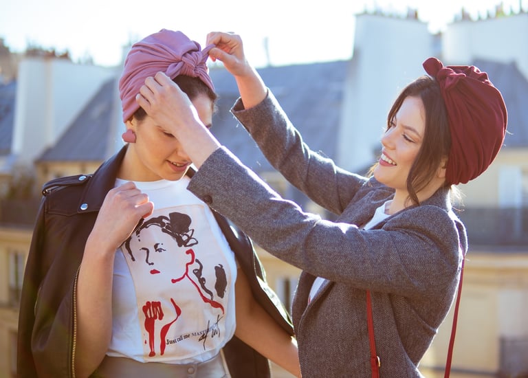 Portrait de deux femmes au turban : geste attentionné d’une amie aidant à placer le turban