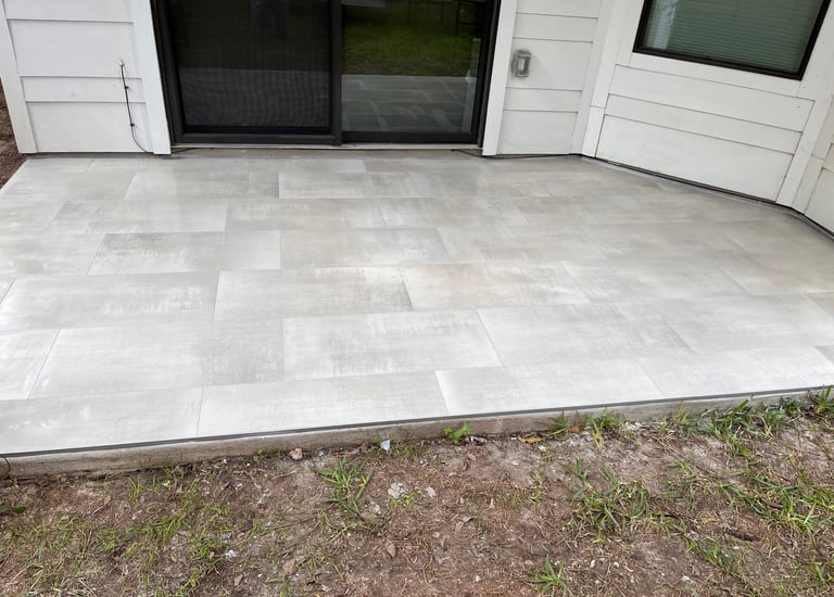 Modern outdoor patio featuring light gray porcelain pavers installed next to a sliding glass door.