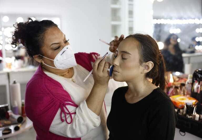 Maquilladora profesional aplicando lápiz labial a una clienta en un estudio de belleza.