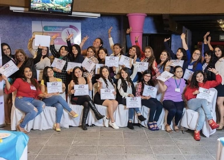 Un grupo de mujeres sonríe mientras sostienen sus certificados de graduación en un taller profesiona