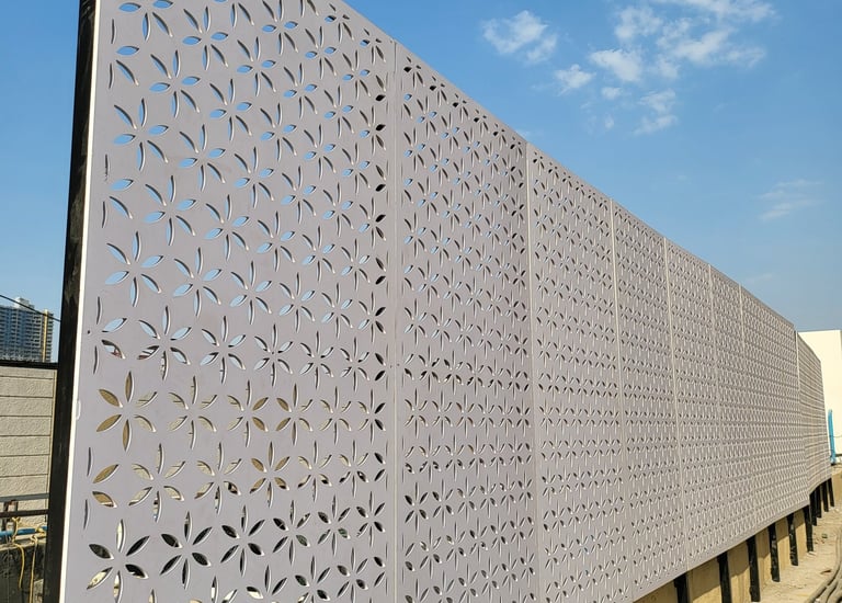 Laser cut metal privacy screen with a decorative floral pattern on a modern outdoor construction site.