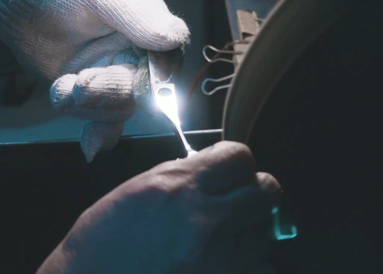 Proceso de afilado de tijeras de peluquería profesionales realizado por artesano en rueda de amolar.