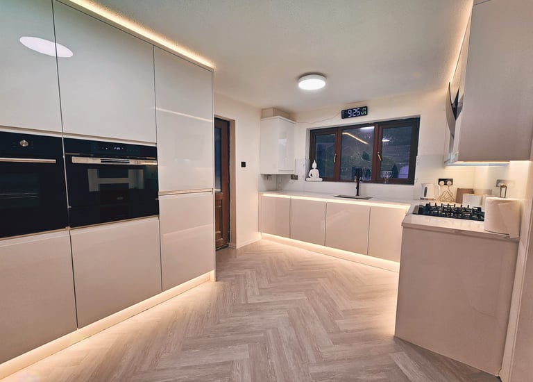 white kitchen with wooden floors and warm cupboard backlighting