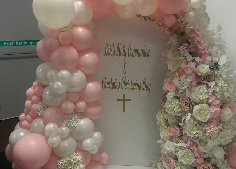 Elegant pink and white balloon arch with floral decorations for a Holy Communion and Christening event.