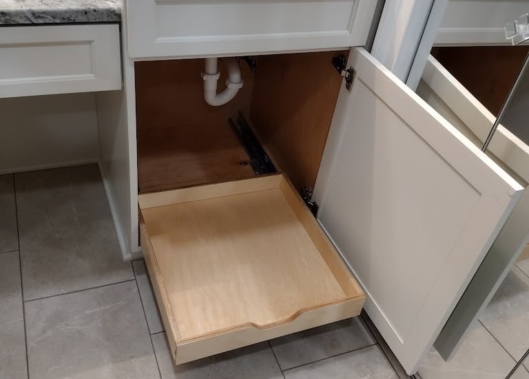 White bathroom vanity with marble countertop and a wooden pull-out cabinet organizer drawer.