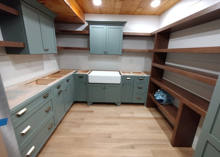 Modern farmhouse pantry with sage green cabinets, farmhouse sink, and open wood shelving.
