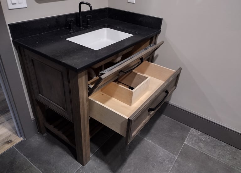 Rustic wood bathroom vanity with black granite countertop, matte black faucet, and open storage drawer.
